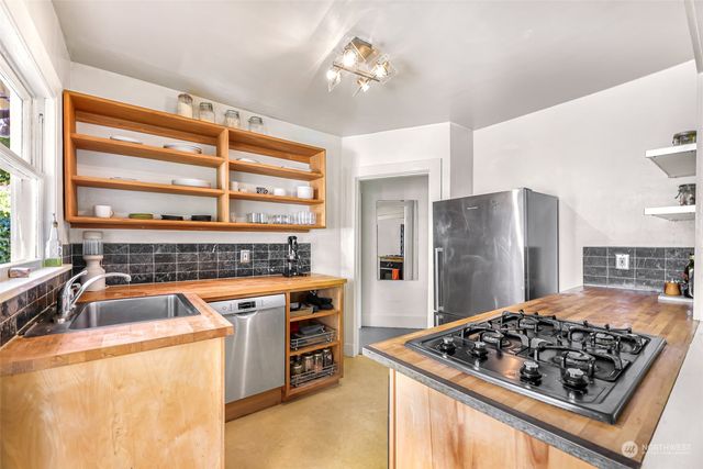 a kitchen with stainless steel appliances granite countertop a stove a refrigerator and a sink with wooden floor