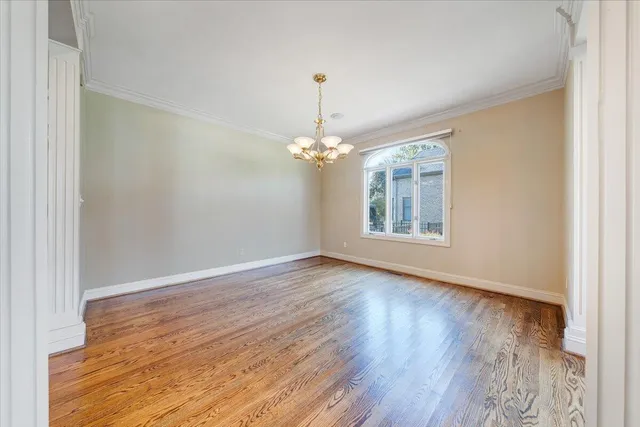 an empty room with wooden floor chandelier and windows