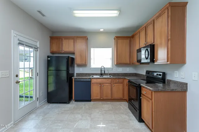 a kitchen with stainless steel appliances granite countertop a refrigerator stove top oven and sink