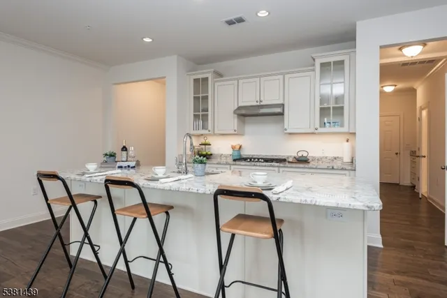 a dining hall with stainless steel appliances granite countertop wooden floor and white cabinets