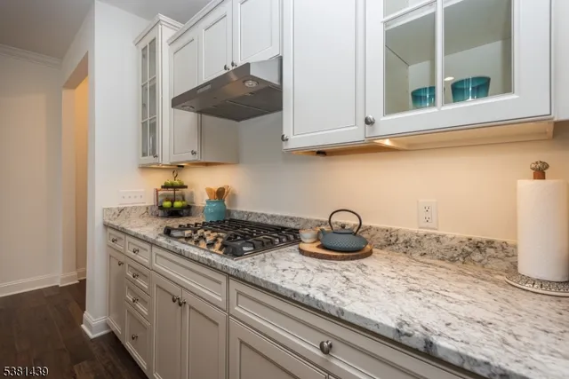 a kitchen with granite countertop white cabinets and a stove