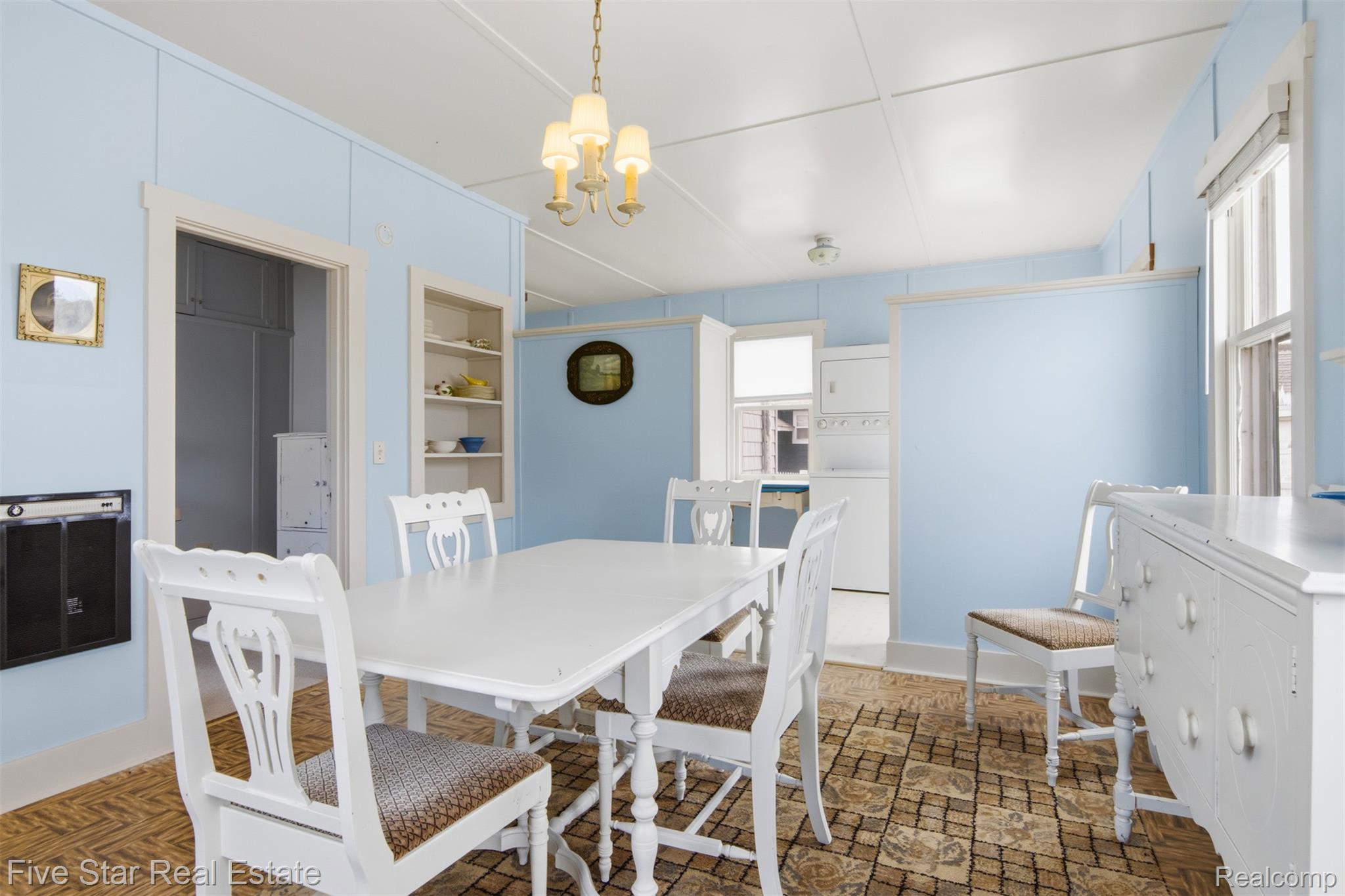 2588 Lakeview Road Onekama, MI 49675 - Photo 16 of 32 Dining area featuring a central chandelier, light blue wall paneling, built-in shelving, and a patterned floor covering