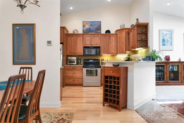 a kitchen with stainless steel appliances granite countertop a stove top oven a sink a dining table and chairs