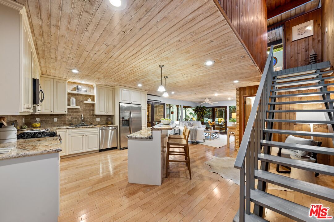 11612 Chenault Street, Unit 4 Los Angeles, CA 90049 - Photo 1 of 28 a living room with stainless steel appliances kitchen island granite countertop furniture wooden floor and a kitchen view