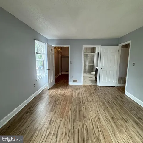 a view of an empty room with wooden floor and window