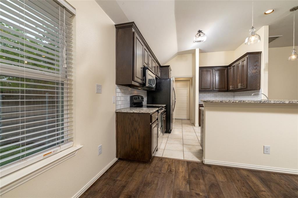 405 Kimbrough Road Azle, TX 76020 - Photo 10 of 39 a kitchen with stainless steel appliances granite countertop a refrigerator a stove and a sink with wooden floors