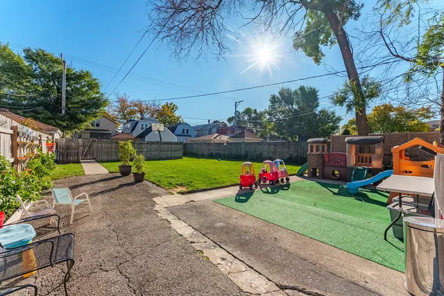 a view of a backyard with a table and chairs potted plants and large tree