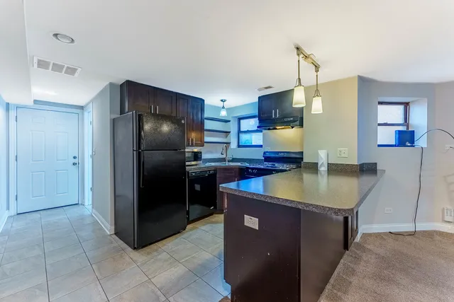 a kitchen with stainless steel appliances granite countertop a refrigerator a stove and a sink