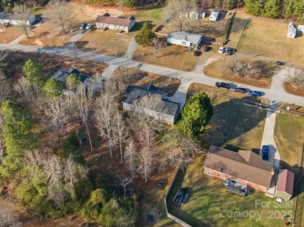 an aerial view of a house with a yard and large trees