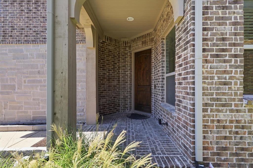 2433 Mare Road Carrollton, TX 75010 - Photo 10 of 37 Covered entry featuring a wood-panel door with brick and stone exterior.