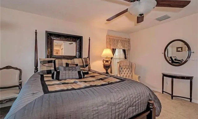 a bedroom with a bed a mirror and lamp on dresser