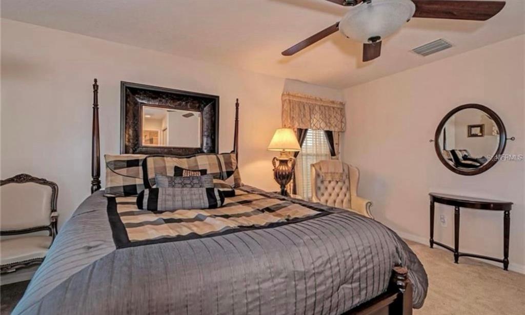15108 Skip Jack Loop Lakewood Ranch, FL 34202 - Photo 15 of 23 a bedroom with a bed a mirror and lamp on dresser