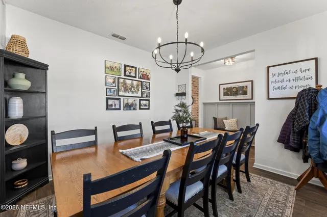 a view of a dining room and livingroom with furniture wooden floor a chandelier