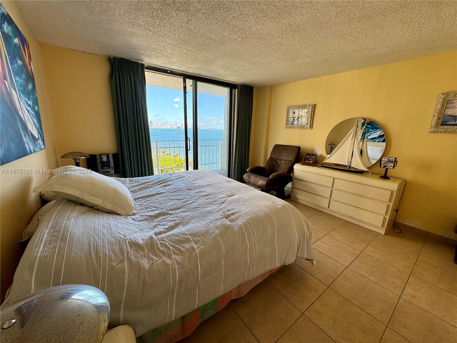 200 Southeast 15th Road, Unit 11F Miami, FL 33129 - Photo 10 of 22 a bed sitting in a bedroom next to a window