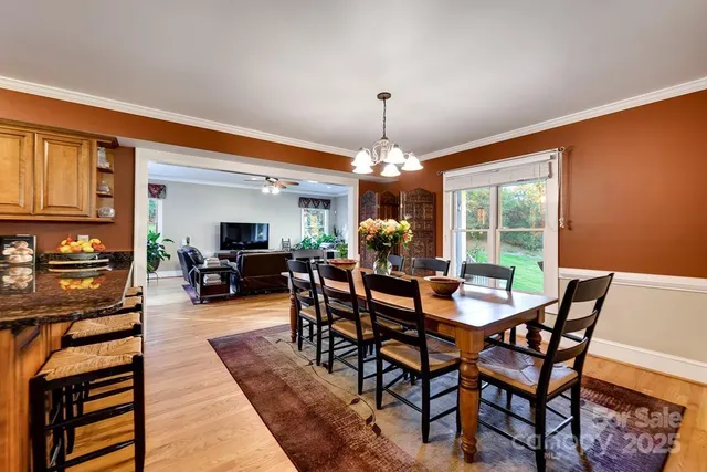 a kitchen with stainless steel appliances granite countertop a refrigerator a stove a sink a dining table and chairs with wooden floor