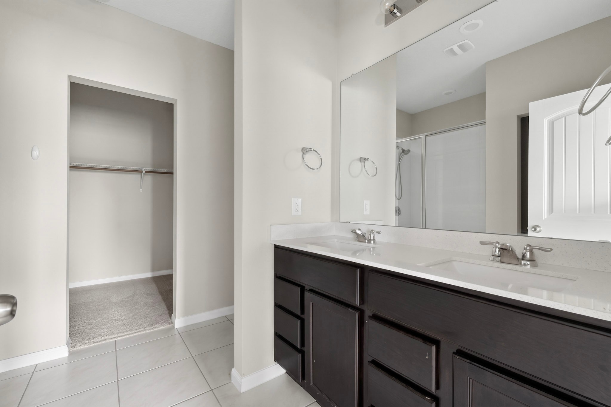 6920 Ranchito Drive Austin, TX 78744 - Photo 7 of 19 A well-appointed primary bathroom featuring a double vanity, large mirror, and tiled flooring.
