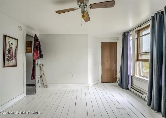 a view of a hallway with wooden floor and a livingroom