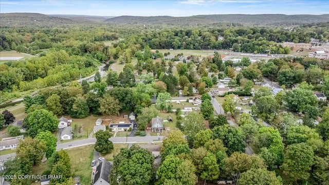 an aerial view of residential house with outdoor space and trees all around