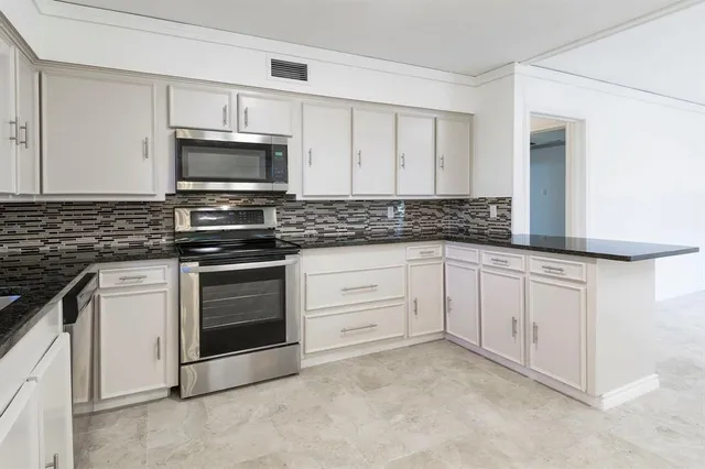 a kitchen with granite countertop white cabinets white stainless steel appliances and a sink