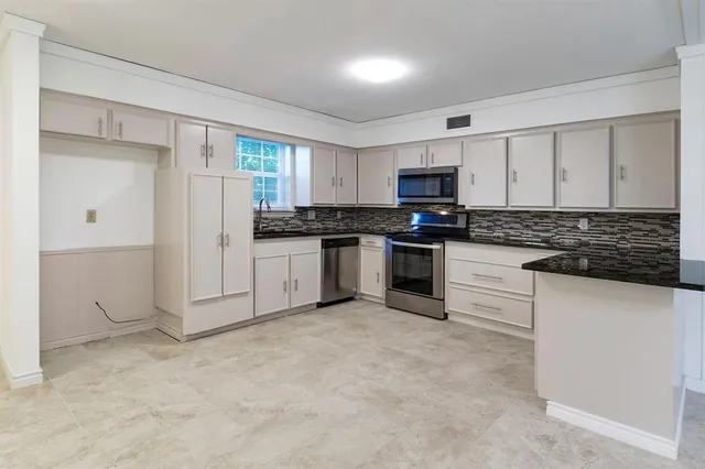 a kitchen with granite countertop a refrigerator sink and cabinets