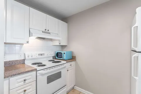 a kitchen with granite countertop white cabinets and white appliances