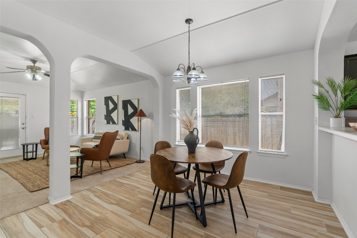 Dining area featuring arched walkways, light wood-style flooring, ceiling fan, and lofted ceiling