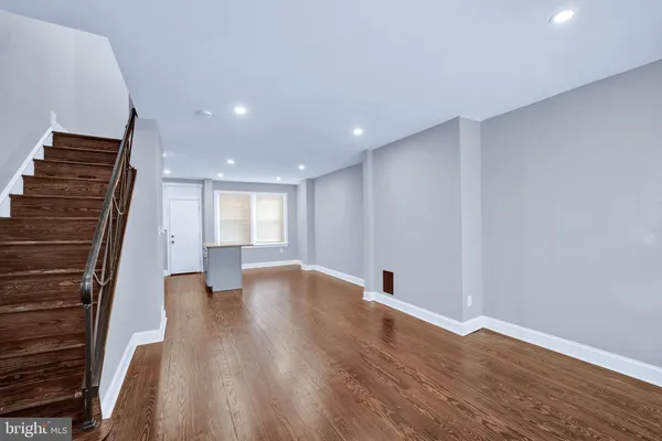 a view of an empty room with wooden floor and stairs