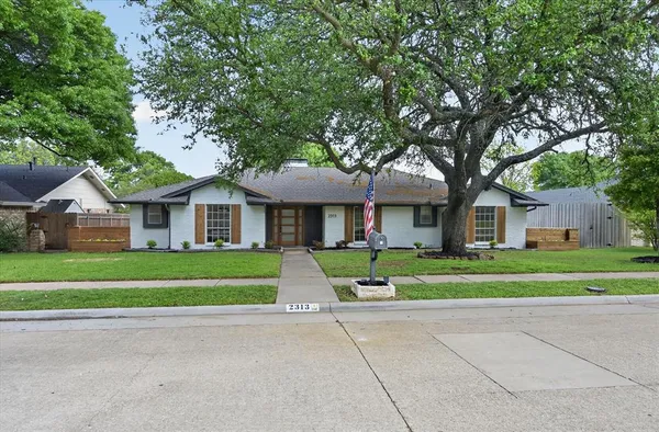 a front view of a house with a yard and trees