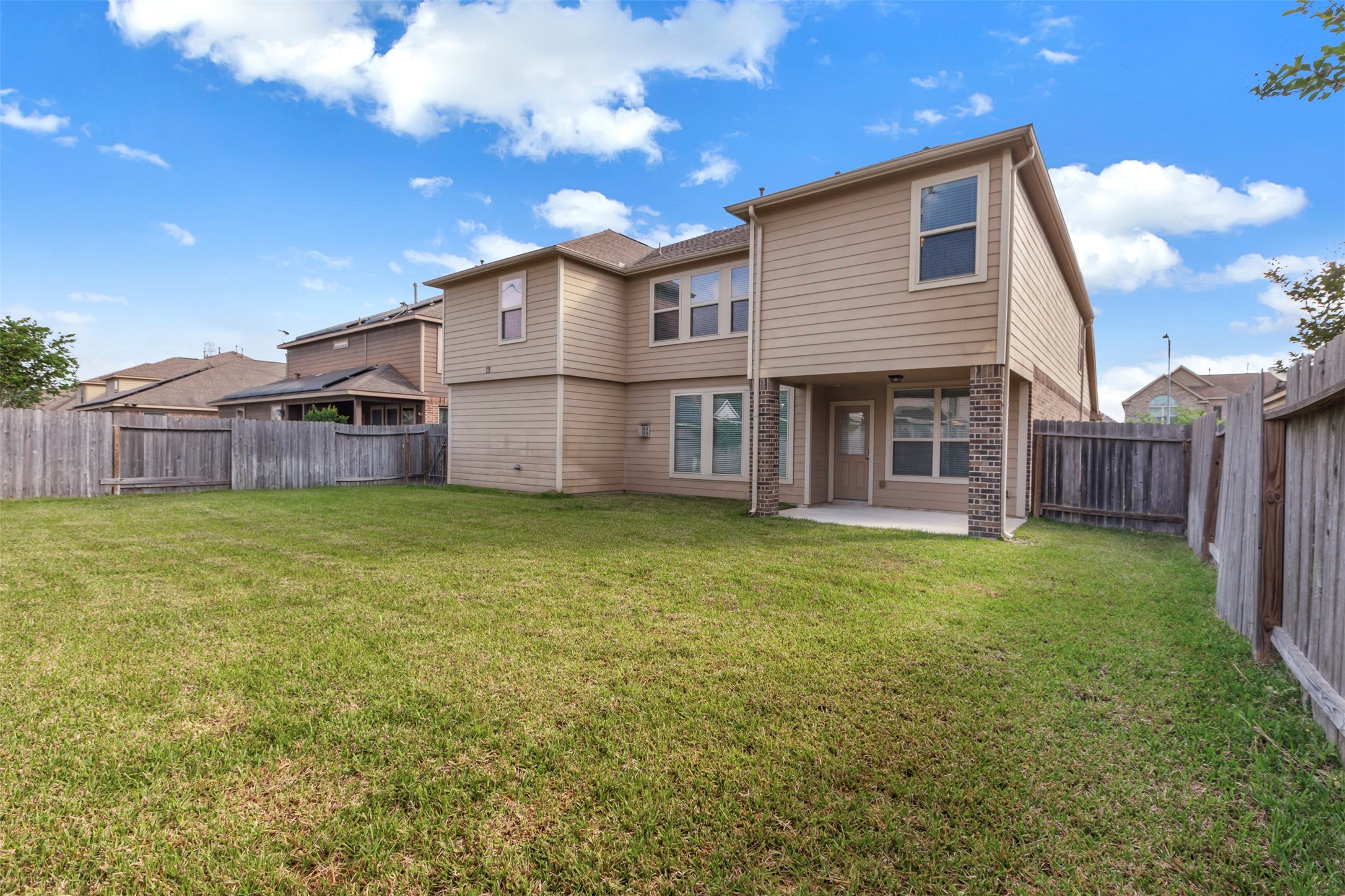 24515 Flora Meadow Drive Spring, TX 77373 - Photo 32 of 34 A large, lush green backyard features a covered patio that offers a landscape view.