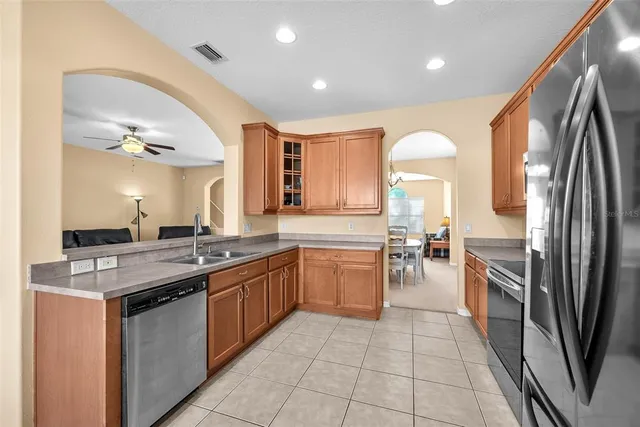 a kitchen with stainless steel appliances granite countertop a stove a refrigerator a sink a dining table and chairs with wooden floor