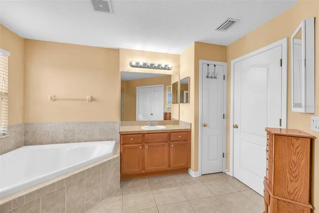 a large spacious bathroom with a double vanity sink a large mirror and a bathtub
