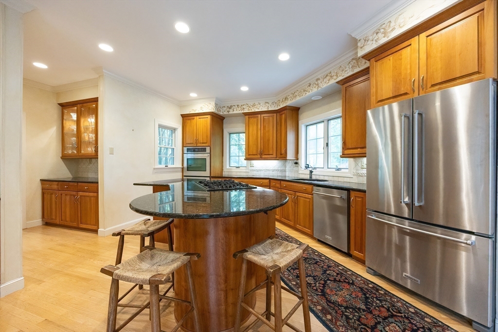 83 High Ridge Road Boxford, MA 01921 - Photo 11 of 42 a kitchen with stainless steel appliances granite countertop a refrigerator a sink dishwasher a stove and a dining table with wooden cabinet
