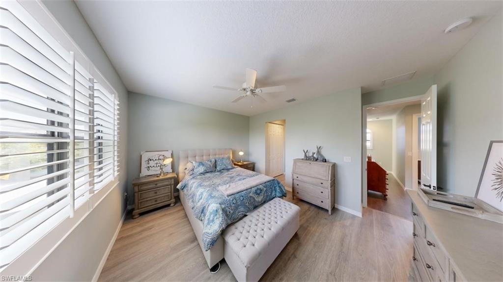 8943 Madrid Circle Naples, FL 34104 - Photo 5 of 13 a bedroom with a large bed and a chandelier