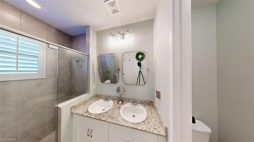 8943 Madrid Circle Naples, FL 34104 - Photo 6 of 13 a bathroom with a granite countertop sink a mirror and shower