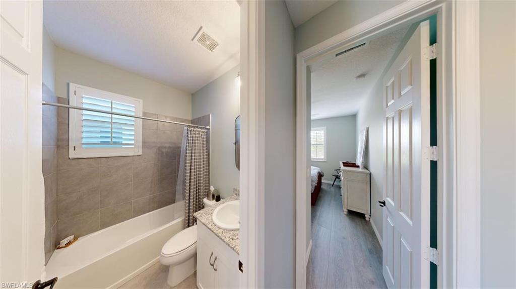8943 Madrid Circle Naples, FL 34104 - Photo 7 of 13 a bathroom with a sink a toilet a tub and shower