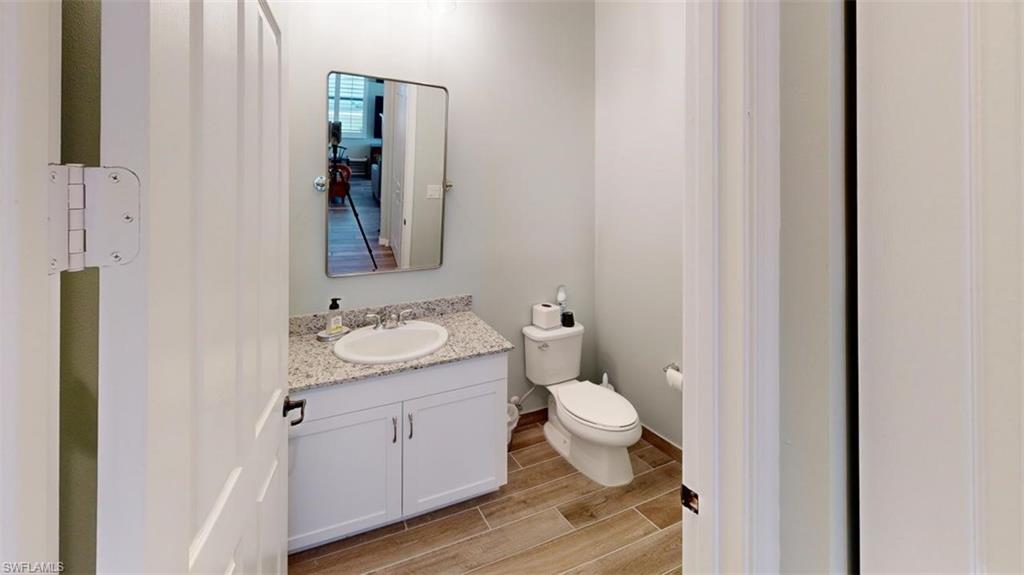 8943 Madrid Circle Naples, FL 34104 - Photo 8 of 13 a bathroom with a granite countertop sink toilet and mirror