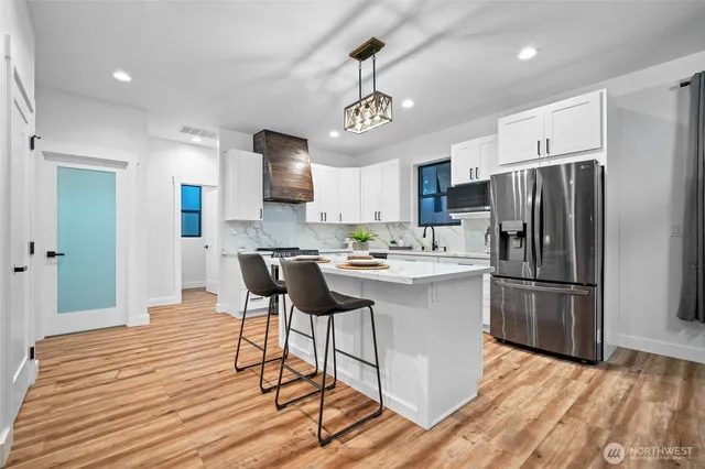 a kitchen with stainless steel appliances granite countertop a refrigerator a stove a sink dishwasher and a refrigerator with wooden floor