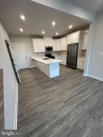 a large kitchen with stainless steel appliances a large counter top a stove a sink and a refrigerator