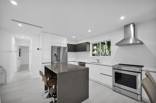 a kitchen with kitchen island stainless steel appliances a sink and a stove
