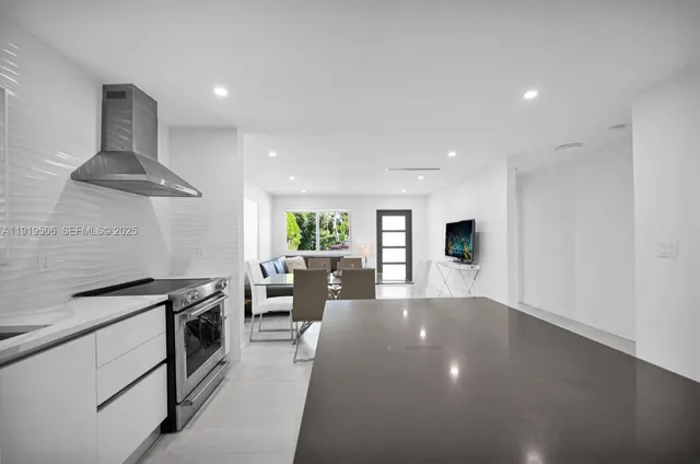 a kitchen with stainless steel appliances a stove a chimney a sink and a refrigerator