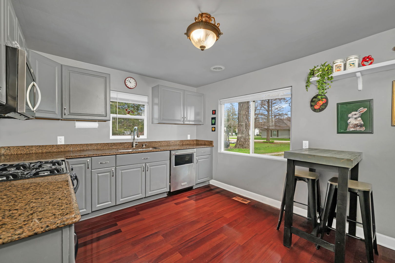136 Grove Street Braidwood, IL 60408 - Photo 10 of 26 a kitchen with granite countertop a stove a sink a dining table and chairs with wooden floor