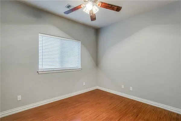 an empty room with wooden floor chandelier and window