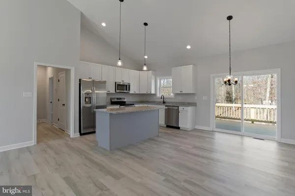 a hall with kitchen island white cabinets and wooden floor
