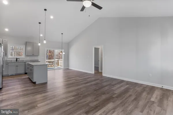a large kitchen with stainless steel appliances granite countertop a refrigerator a sink dishwasher a oven and a kitchen island with wooden floor
