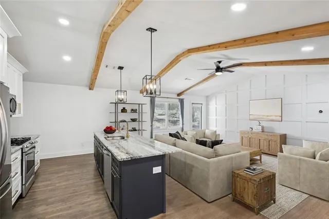 a living room with furniture kitchen view and a wooden floor