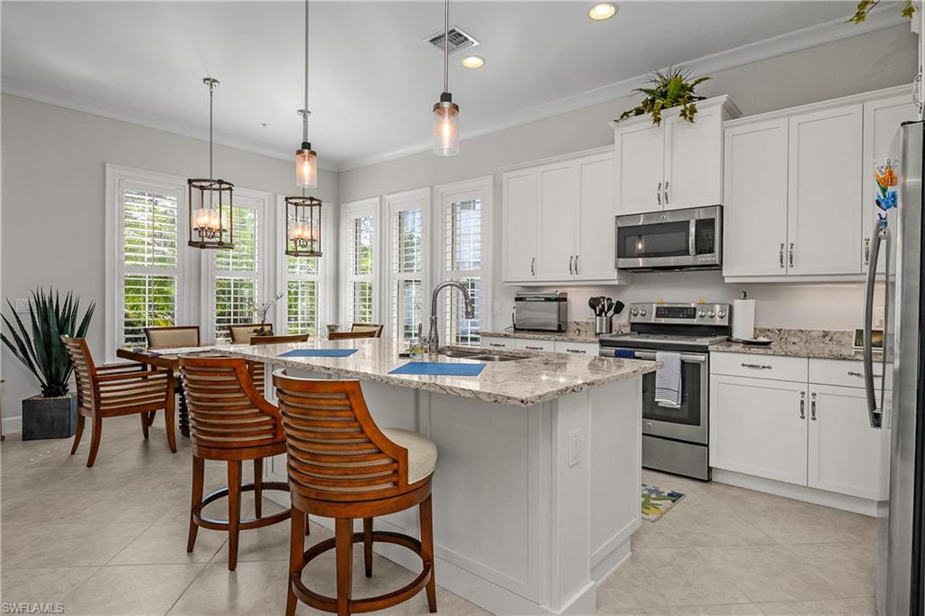 6552 Dominica Drive, Unit 101 Naples, FL 34113 - Photo 9 of 50 a kitchen with stainless steel appliances granite countertop a stove top oven a sink a dining table and chairs