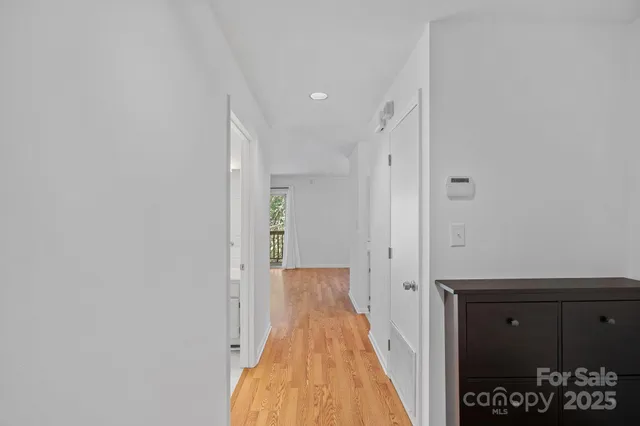 a view of a hallway with wooden floor and a bathroom
