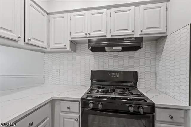 a kitchen with granite countertop white cabinets and stainless steel appliances