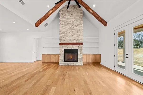 an empty room with wooden floor chandelier and windows