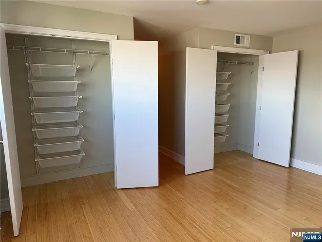 a view of an empty room with closet and wooden floor